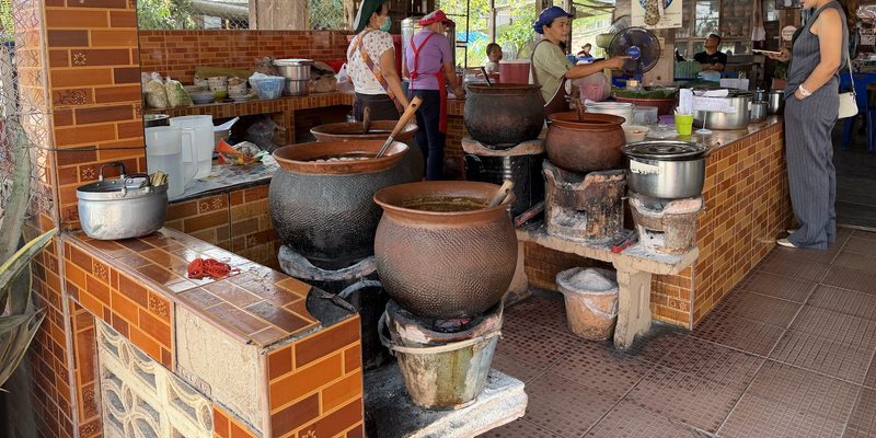 ครัวเปิดหน้าร้าน หม้อดินใบใหญ่ตั้งบนเตาถ่านเรียงตามเคาน์เตอร์ปูกระเบื้อง