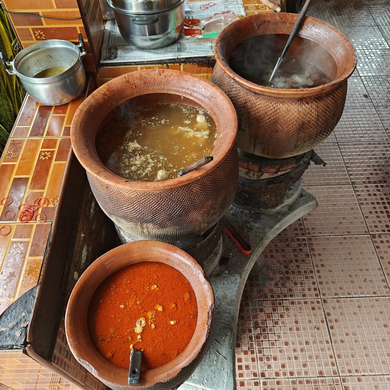 หม้อดินใส่น้ำแกงหลายใบอุ่นอยู่บนเตาถ่าน